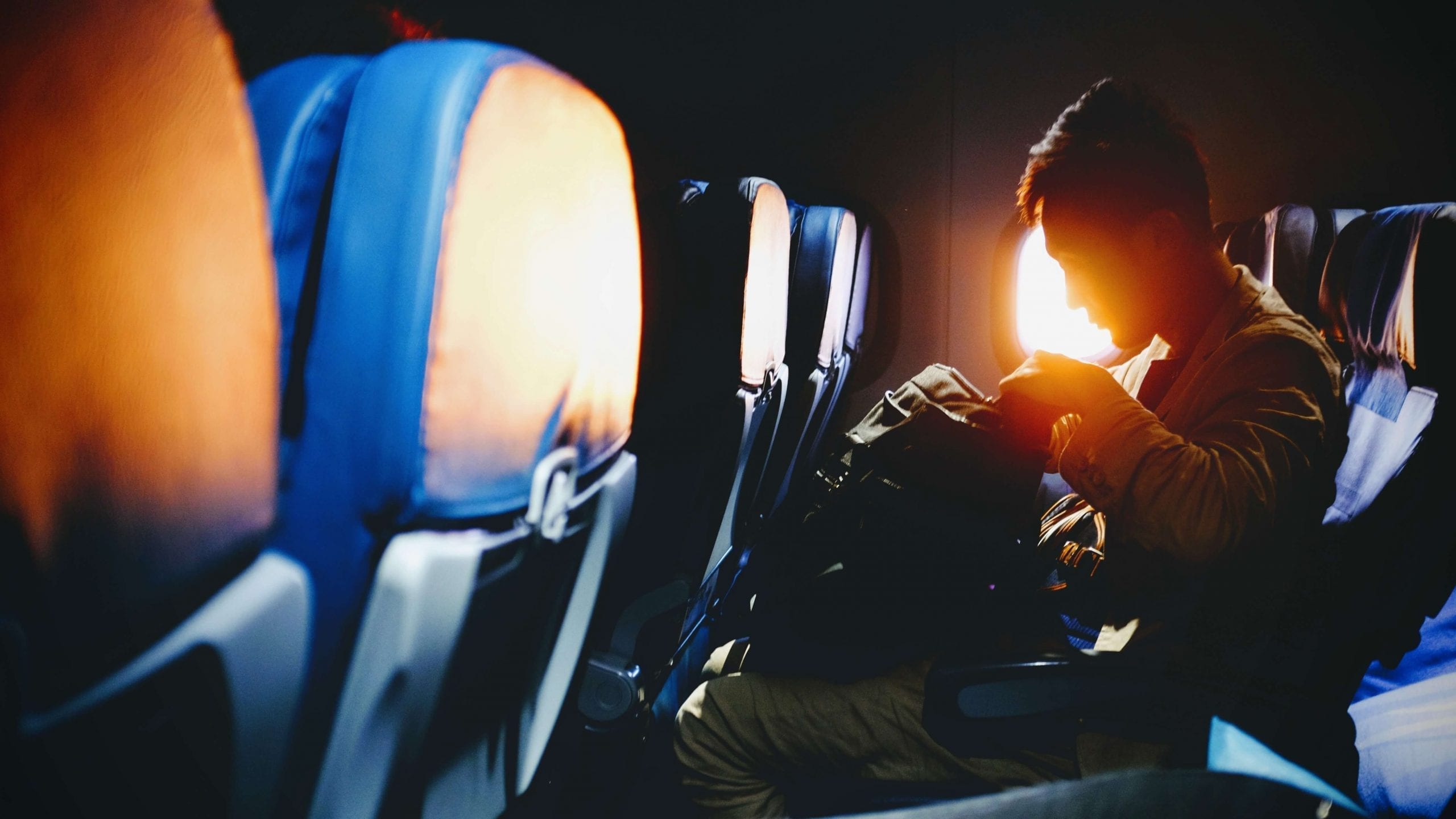 Man sit in a plane searching in his bag