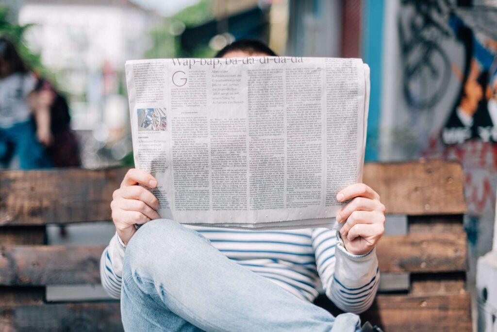 Man reading newspaper on a bench