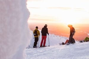 Skiers at the top of a mountain at sunset