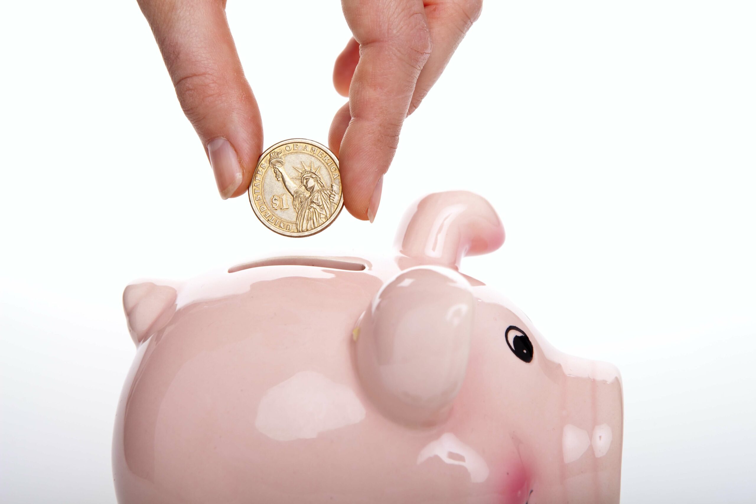 hand dropping a coin into a piggy bank