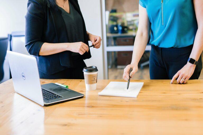 two people discussing plans at a table with a laptop
