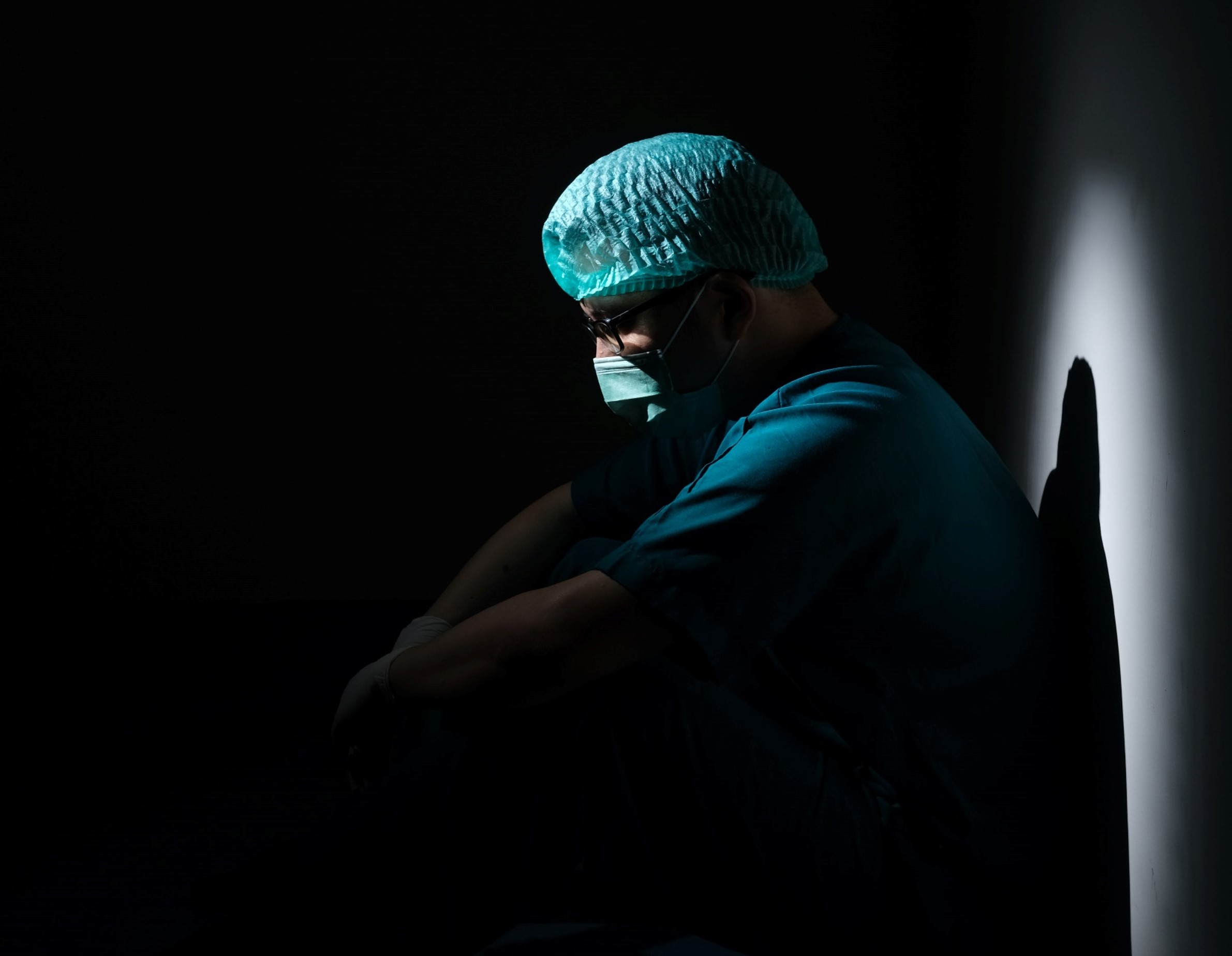 surgeon in a black room lit by a spotlight